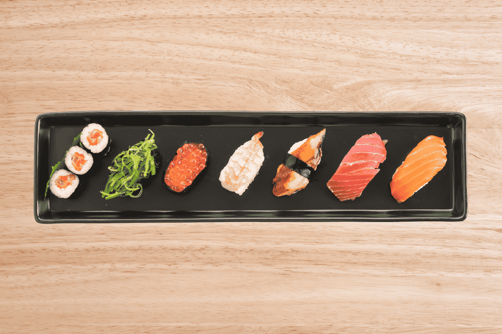 Assorted sushi pieces artfully arranged on a black tray, highlighting contemporary plating and textures—ideal for discussing modern twists on traditional omakase.