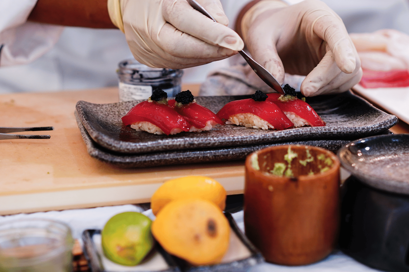 Chef slicing fresh fish for sushi on a wooden board, showcasing precise knife work during an omakase service