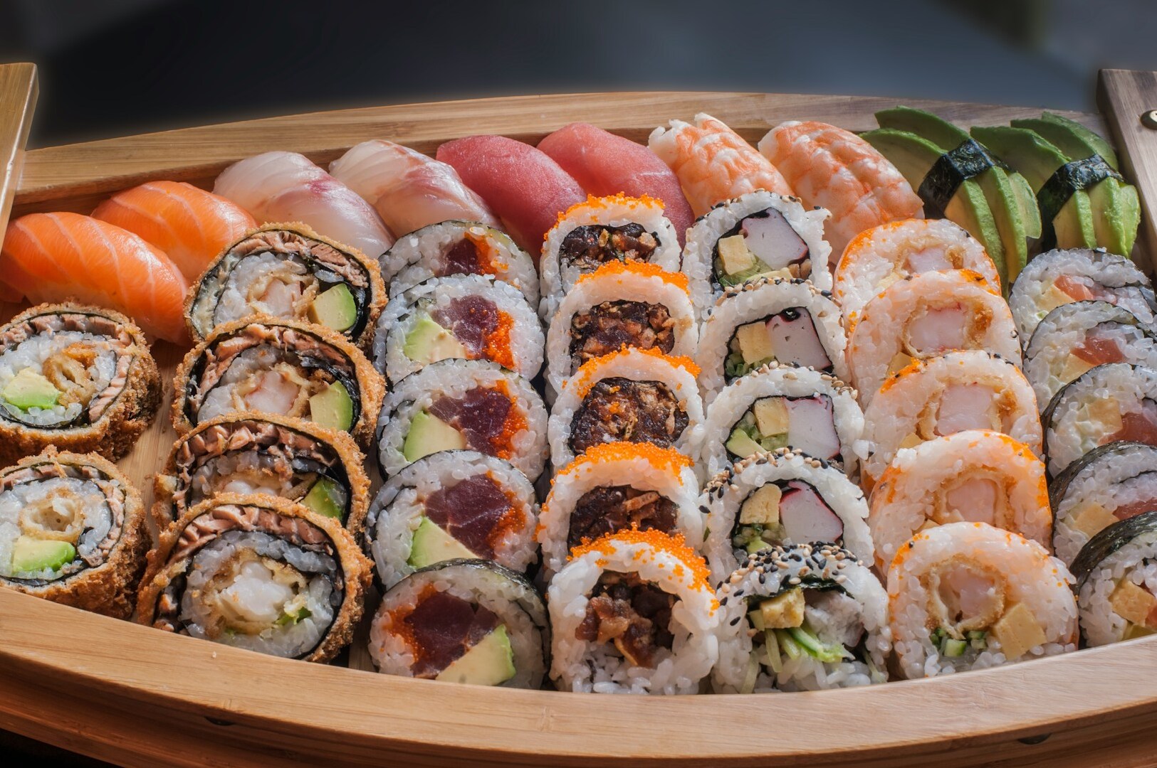 A wooden tray displaying an assortment of sushi and various dishes, highlighting the omakase dining experience.