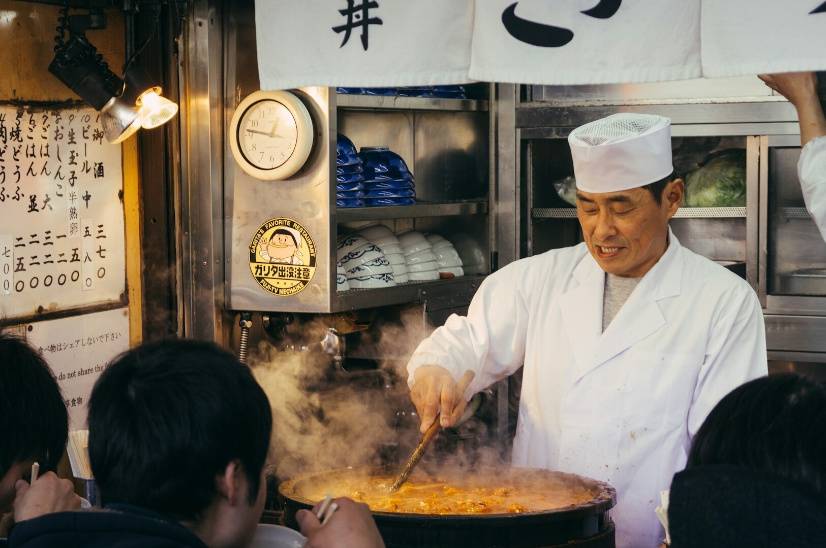 A Japanese chef stands serving soup, representing culinary expertise in Japanese cuisine in Singapore.