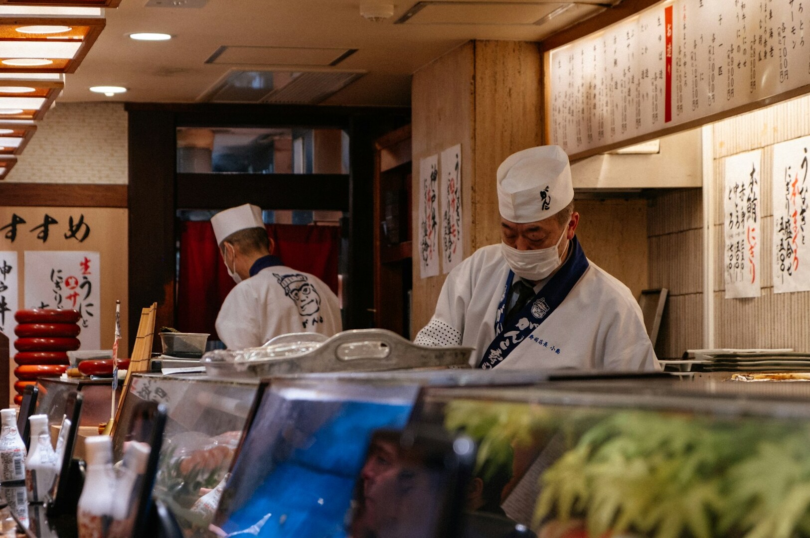 A chef in a white hat skillfully prepares dishes in a restaurant, highlighting the art of Japanese cuisine.