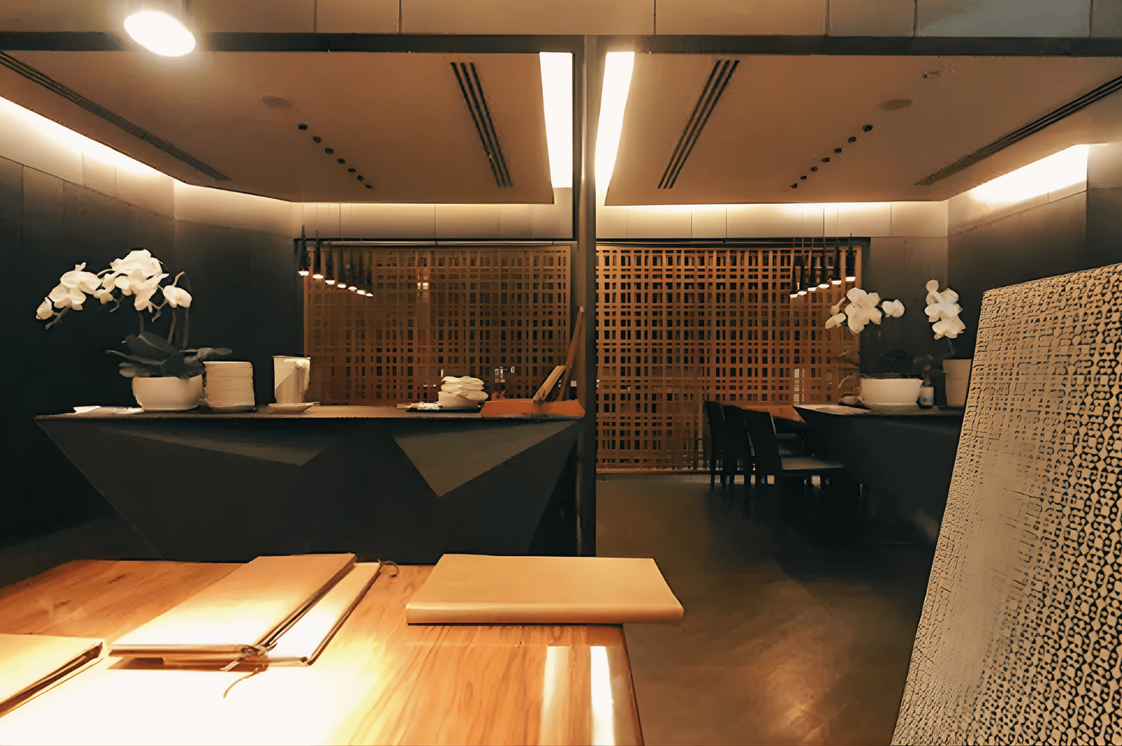 Warm, minimalist restaurant interior with wooden tables, soft lighting, and orchids—setting the scene for a refined omakase experience.