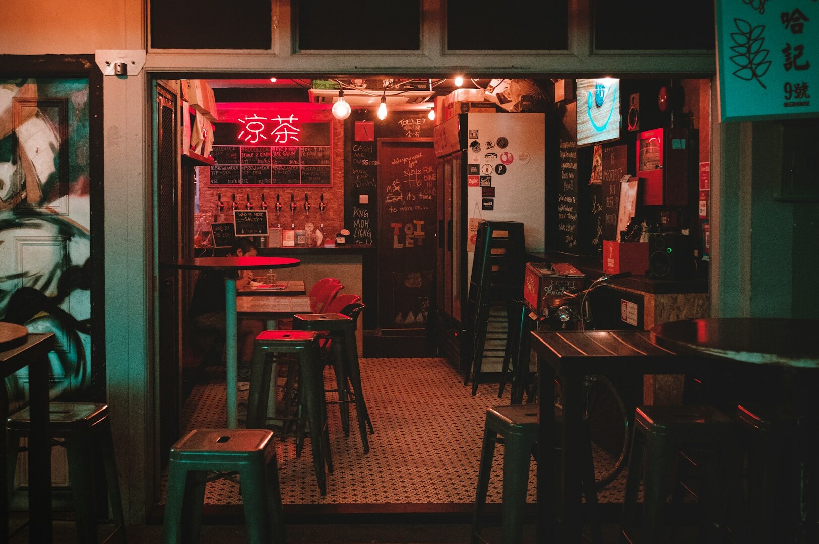 Interior of a Japanese restaurant bar with stools and a vibrant neon sign, showcasing its Michelin-starred status.