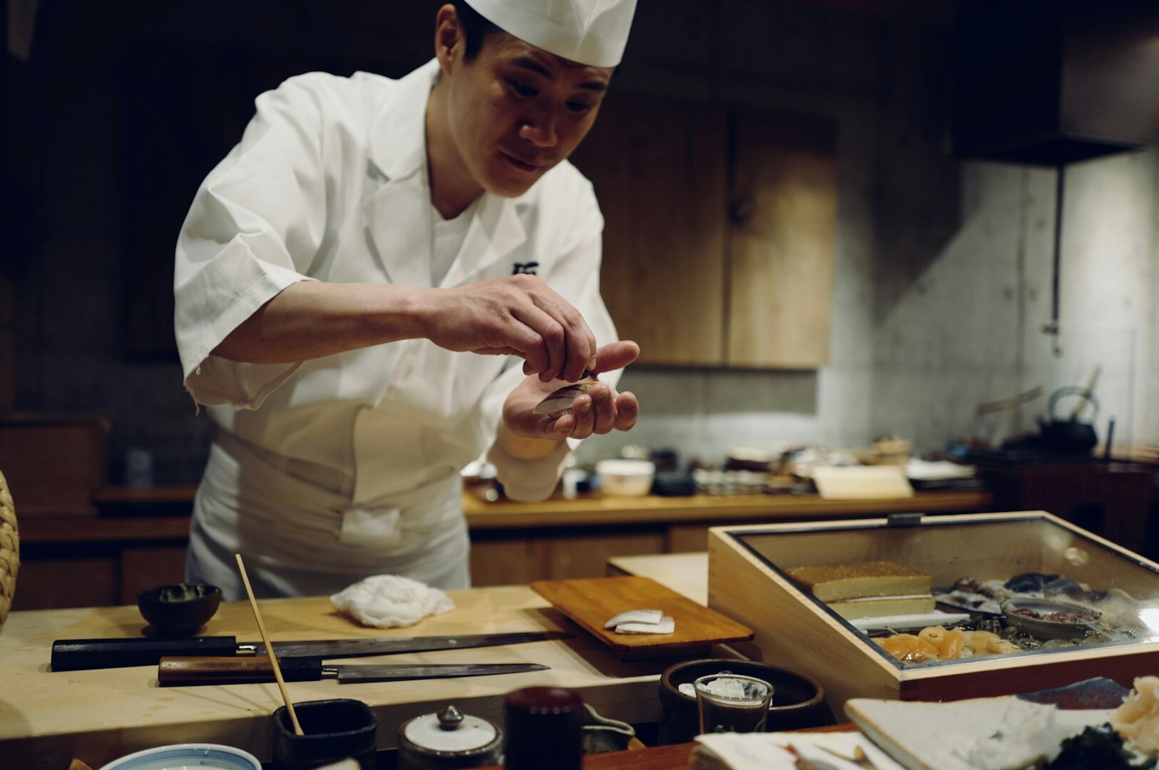 A chef skillfully prepares food in a kitchen, embodying the trust and tradition of the omakase dining experience.