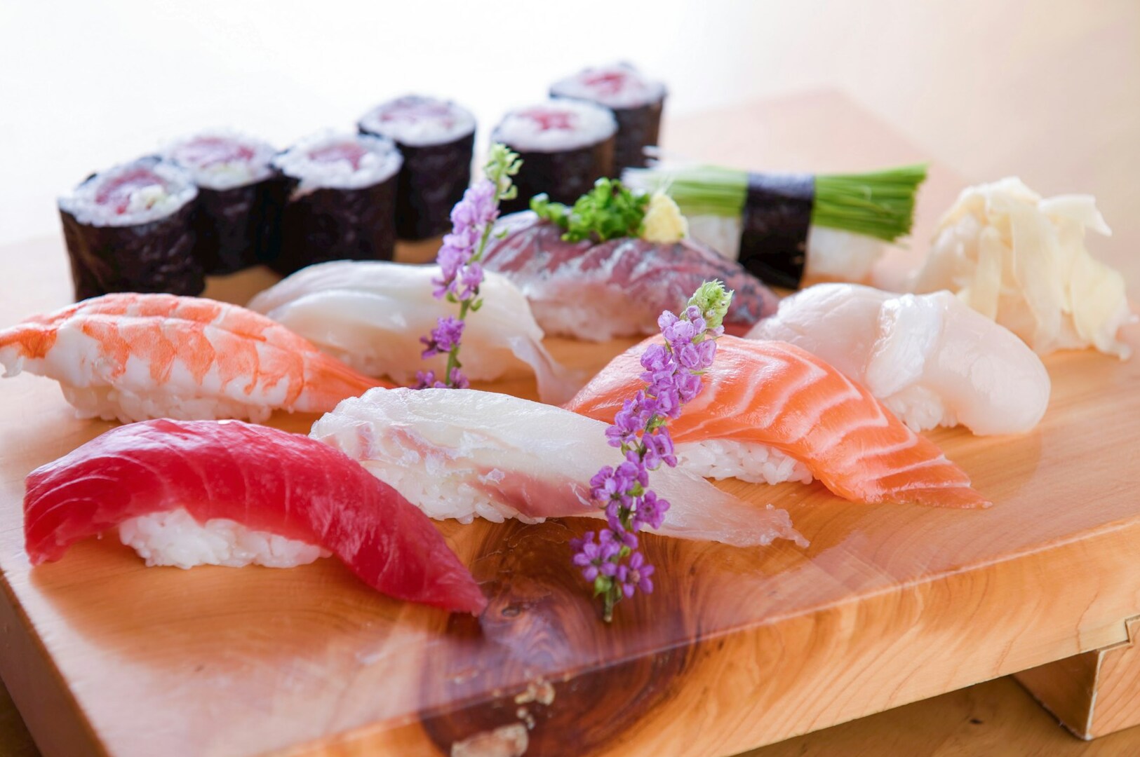 A wooden cutting board featuring various sushi and seafood, the quality standards of a premier sushi buffet.