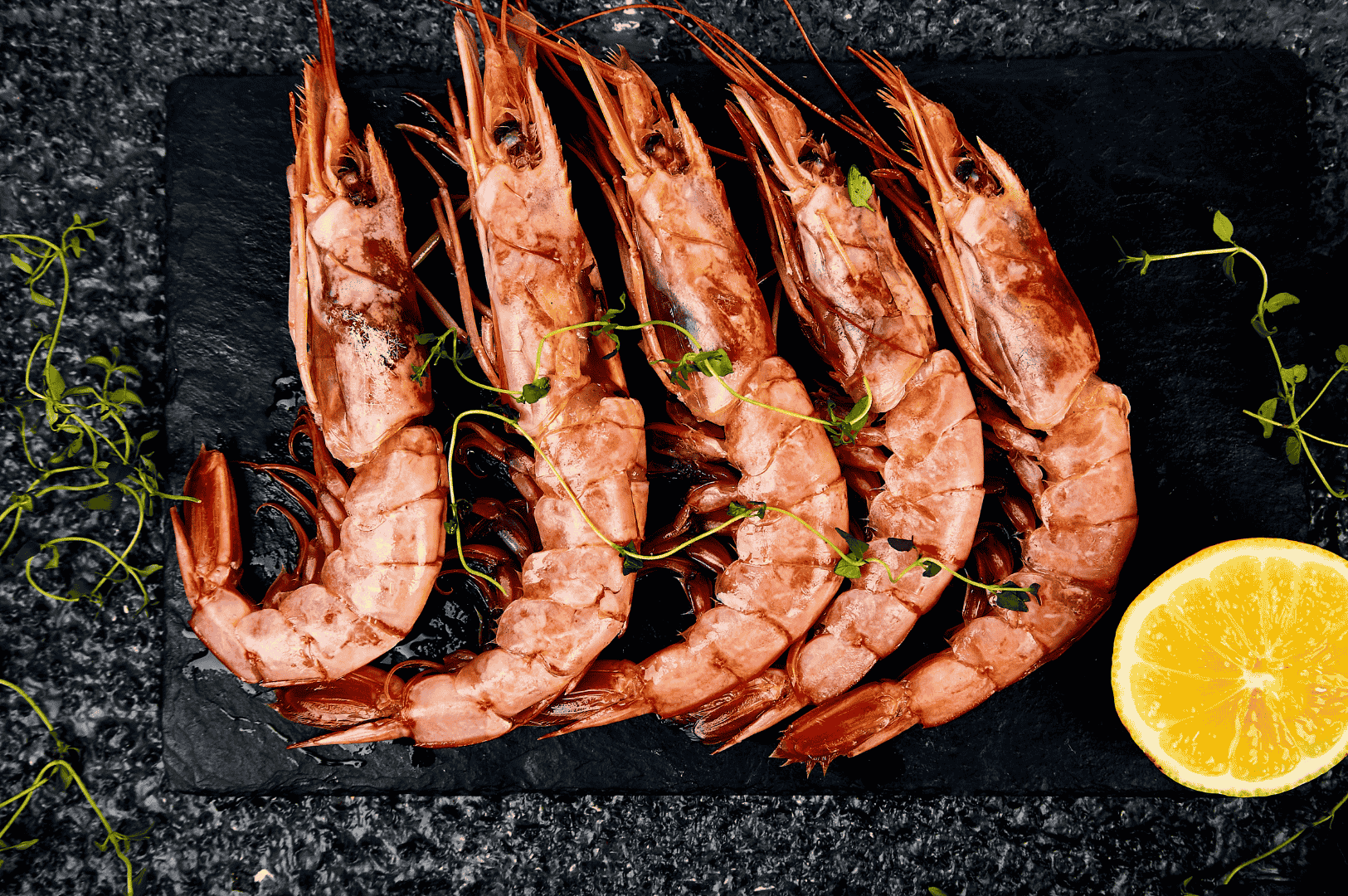 Fresh Japanese Tiger Prawns, lightly cooked and presented whole with heads and tails intact, arranged on a black slate alongside sprigs of herbs and halved lemon—an elegant expression of Yamato’s tempura omakase, where pristine seafood and restrained technique invite expert scrutiny.