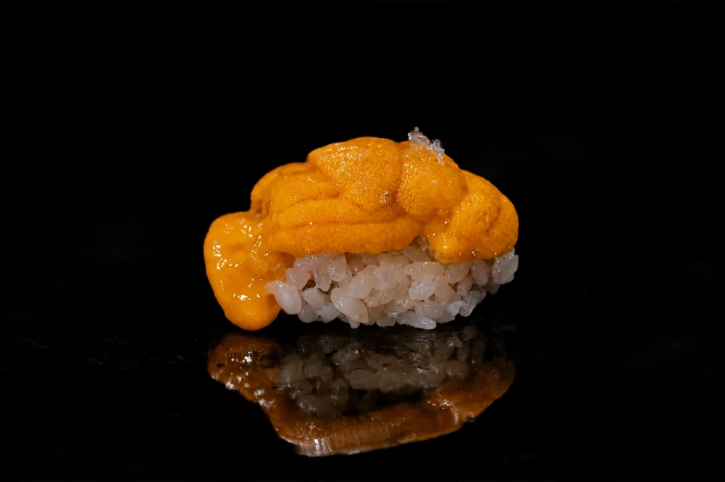 A single sushi piece displayed on a black background, showcasing the elegance of a premium omakase offering.