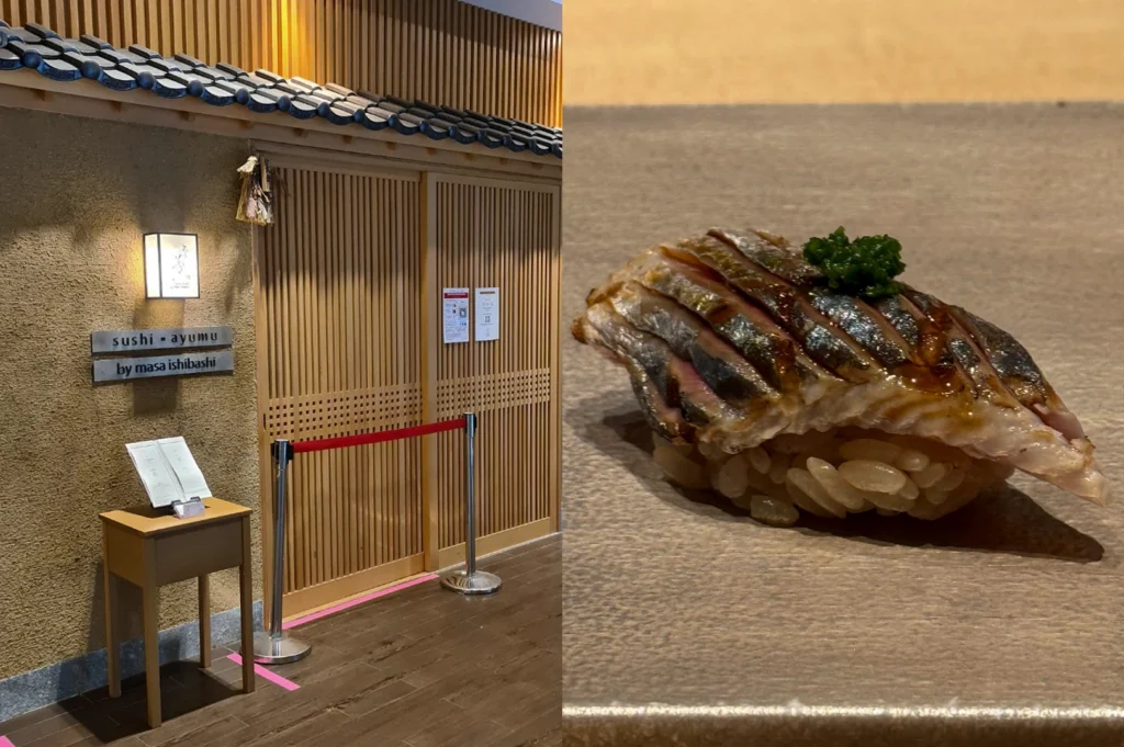 A split-screen image showcasing the traditional entrance and a delicate nigiri piece. On the left, the "Sushi Ayumu by Masa Ishibashi" storefront features a textured sand-colored wall, a minimalist wooden sliding door with vertical slats, and a small podium holding a menu. On the right, a close-up shot features a piece of nigiri sushi where the fish is expertly scored, lightly seared, and glazed with a dark soy reduction, topped with a small pinch of bright green garnish and resting on seasoned brown rice.