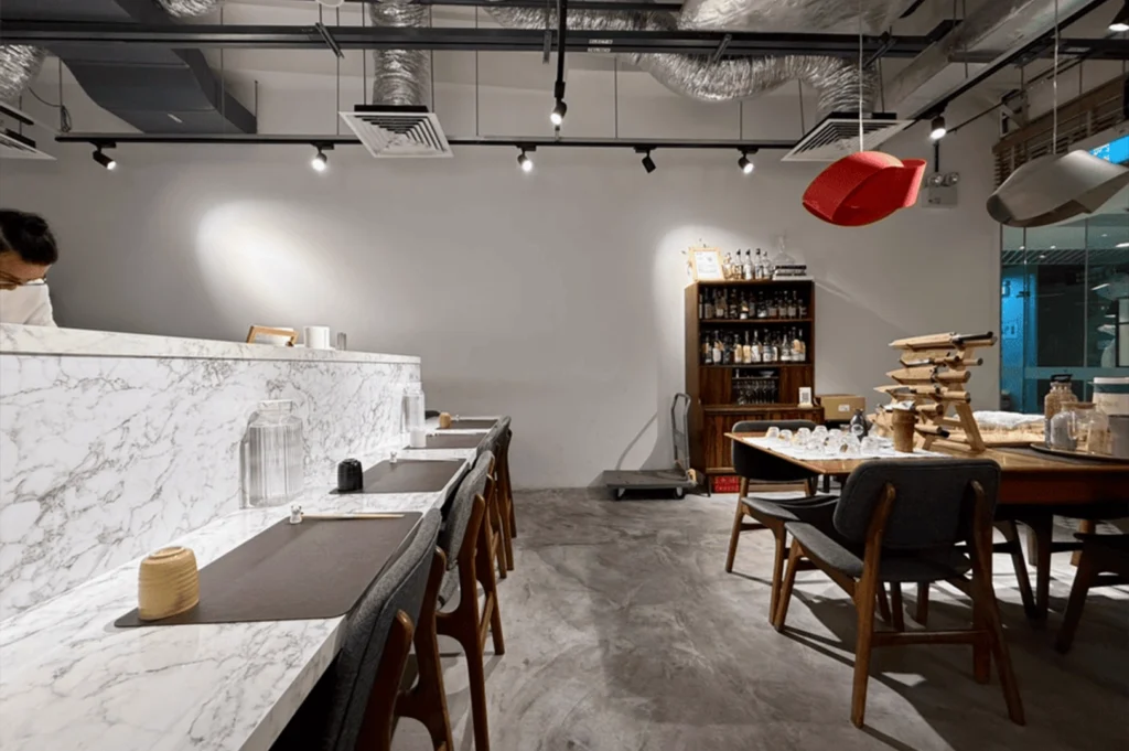 Interior of Russculler Omakase, showcasing elegant marble countertops and a spacious dining table in a serene setting.