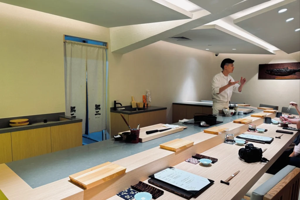 A man in front of Sushi Muni, a sushi bar emphasizing ingredient purity and quality.