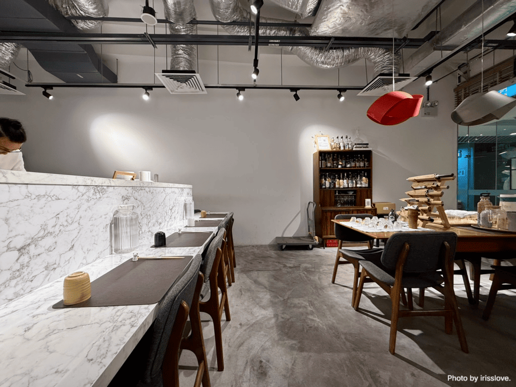 Interior of Russculler Omakase, showcasing elegant marble countertops and a spacious dining table in a serene setting.