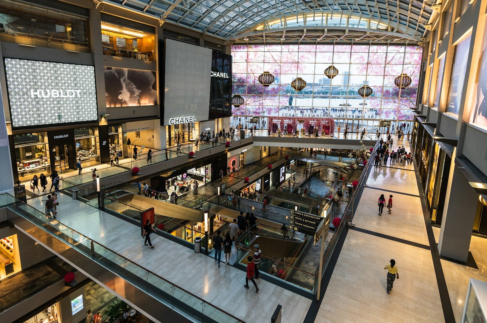 The image depicts the interior of a modern shopping mall in Singapore, showcasing sleek lines and innovative architecture. This vibrant area attracts a new generation of diners eager to enjoy high-quality Japanese fare and fusion cuisine at popular restaurants like Omote, where reservations are often needed to taste their distinct flavor profiles.