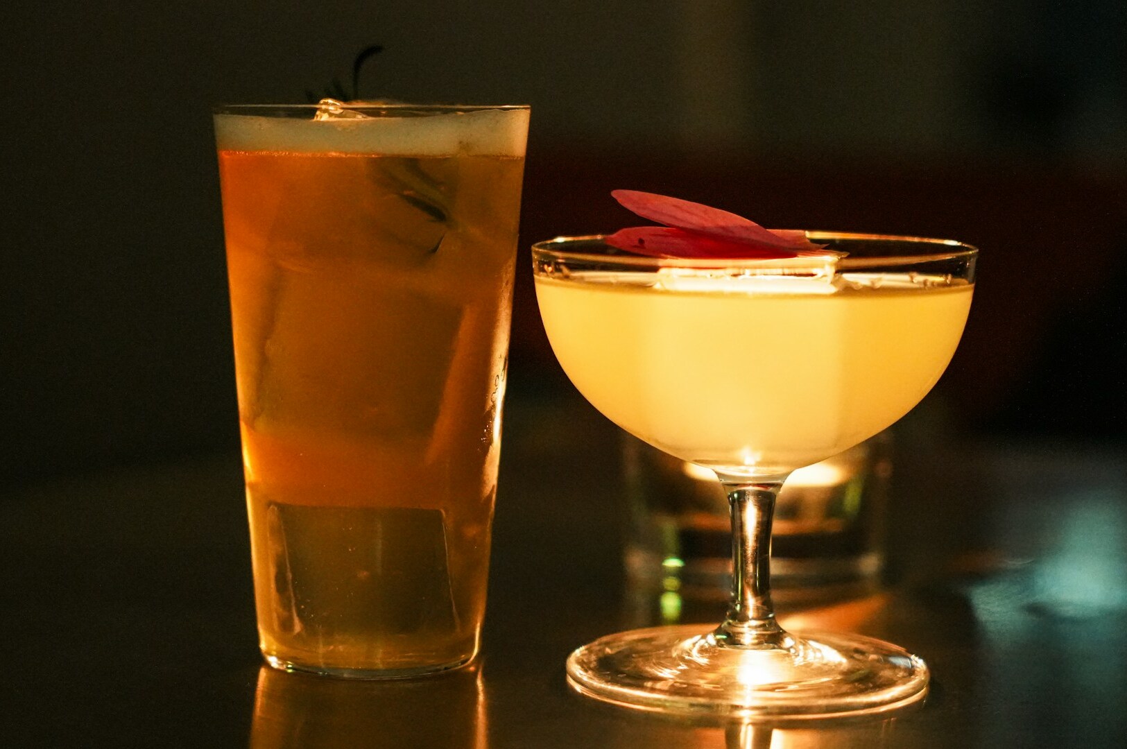 A vibrant cocktail adorned with colorful edible flowers and an artistic garnish sits elegantly, inviting diners to experience its distinct flavor profile. This high-quality drink embodies omote's philosophy of fusion cuisine, offering a delightful treat for the taste buds.