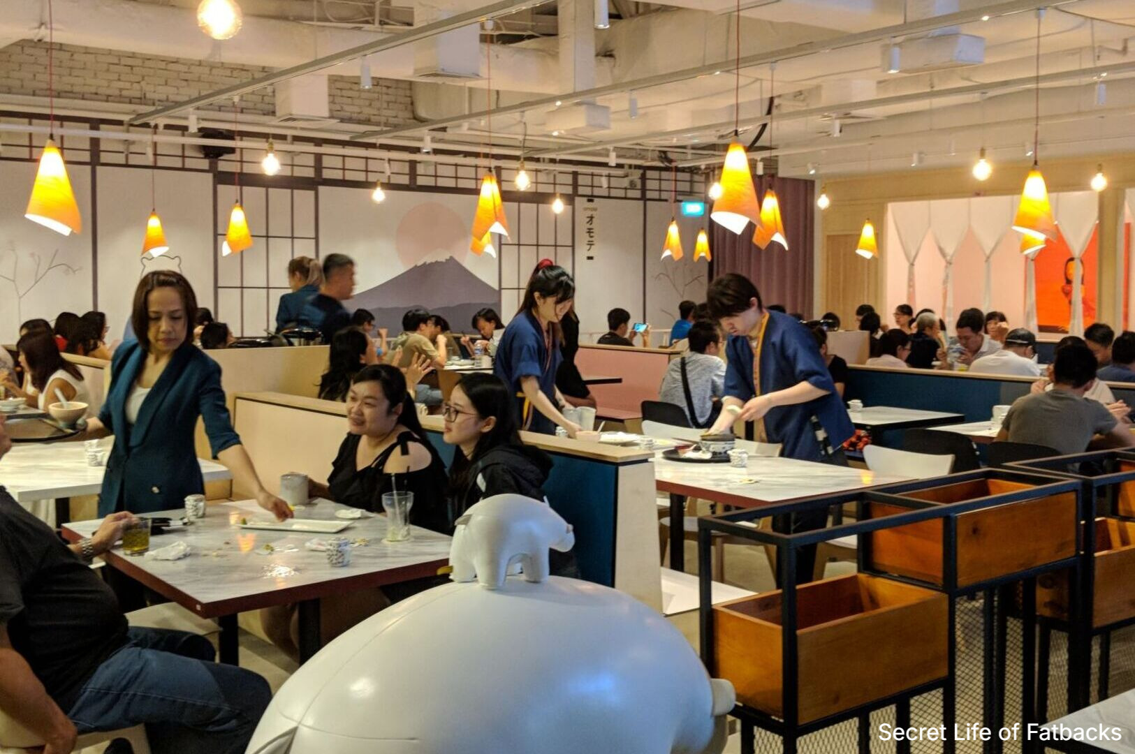 Diners seated at tables in Omote Thomson Plaza, enjoying their meals in a lively restaurant atmosphere.