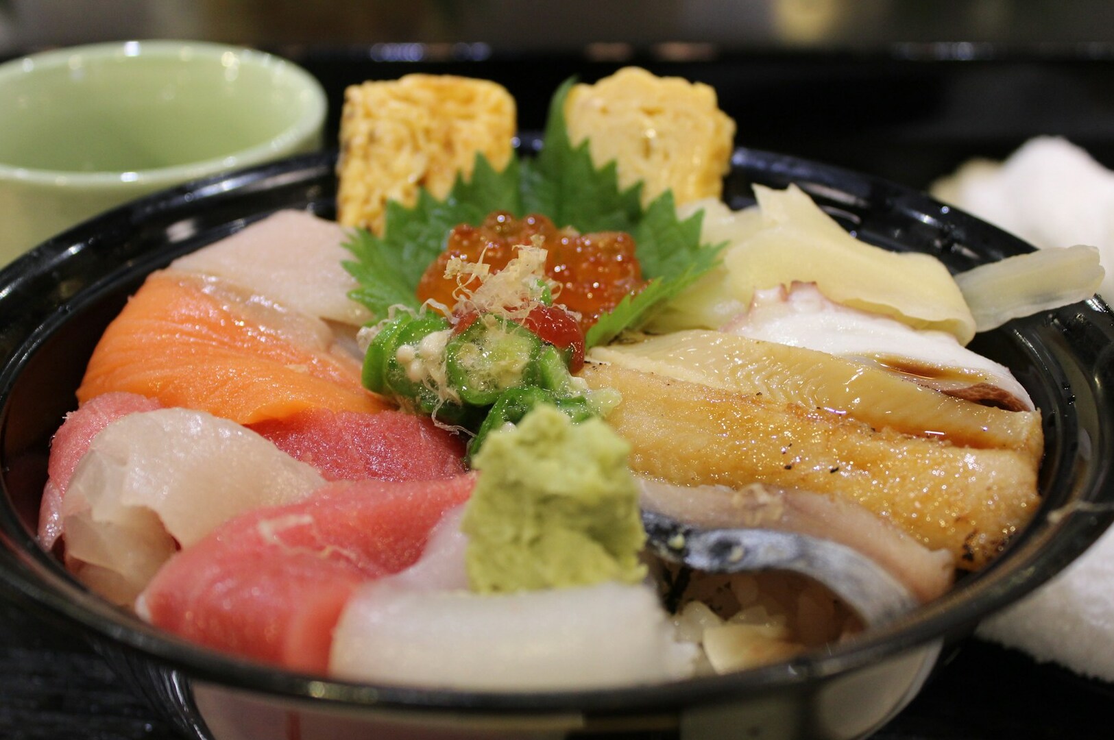 A colorful bowl of chirashi sushi with assorted fish, displayed at Omote Thomson Plaza.