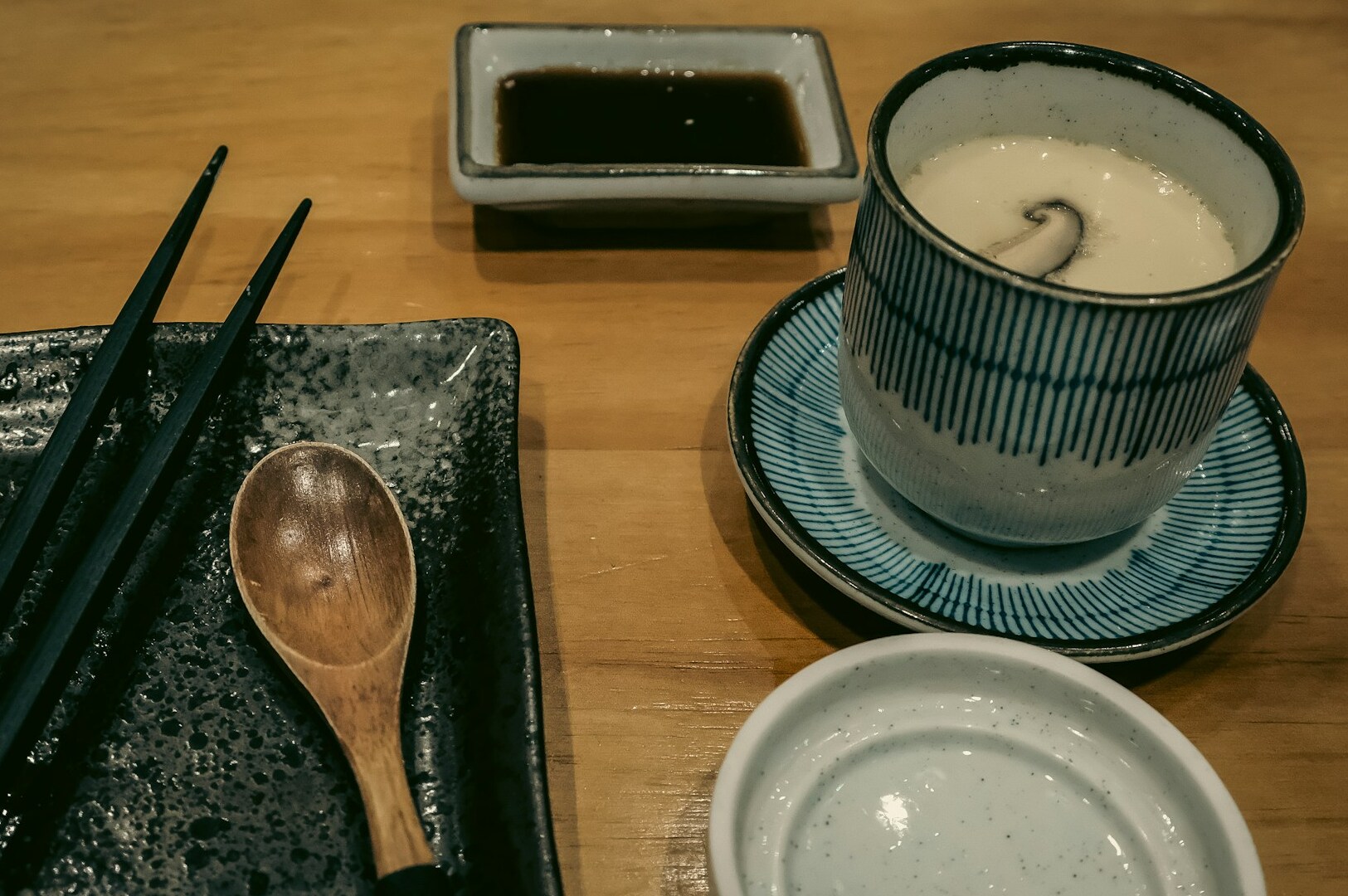 A bowl of soup accompanied by chopsticks sits on a table, showcasing the serene dining experience at Omote Thomson Plaza.