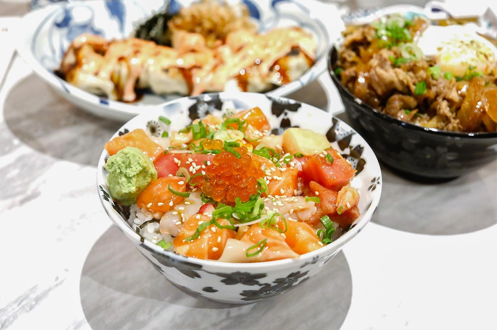 Close-up of Omote's chirashi don, a bowl of rice topped with mixed sashimi cubes, salmon roe (ikura), and a dollop of wasabi.