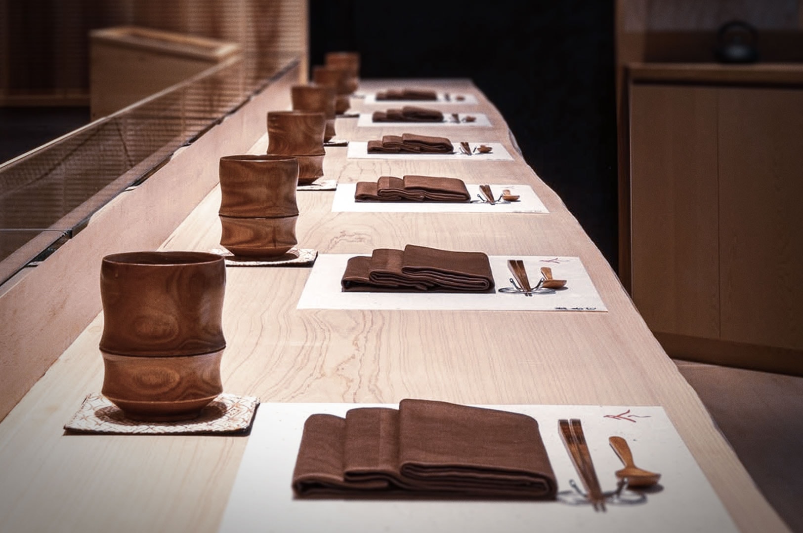 Omakase-style dining setup featuring minimalist tableware on light wood counter.
