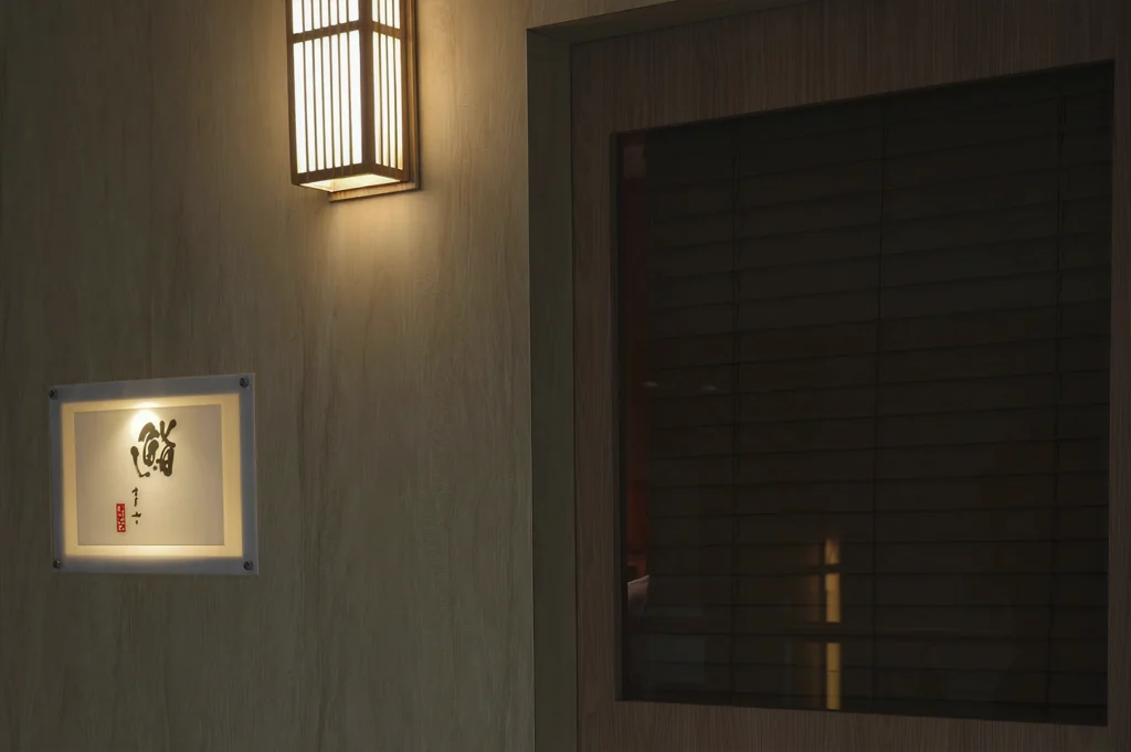 The minimalist exterior entrance of a Japanese restaurant at night. A warm, rectangular lantern glows above a sleek wooden door with dark blinds. To the left, a small, backlit frosted glass sign features elegant black Japanese calligraphy.