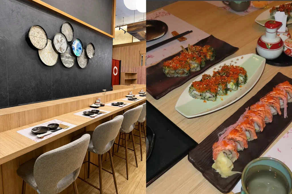 A side-by-side split layout showing both the modern dining area and the food at a Japanese restaurant. On the left side, a sleek wooden sushi bar counter is lined with light gray high-top upholstered chairs, where each place setting is precisely arranged with dark plates, a placemat, and chopsticks on a long wooden counter under a dark gray textured wall adorned with a cluster of decorative, patterned circular plates. On the right side, a top-down close-up showcases a light-colored wooden table filled with several platters of specialty sushi rolls heavily topped with bright orange tobiko (fish roe) and green garnishes, alongside a long ceramic dish featuring salmon-draped rolls topped with microgreens and pickled ginger, with Japanese condiment bottles resting nearby.